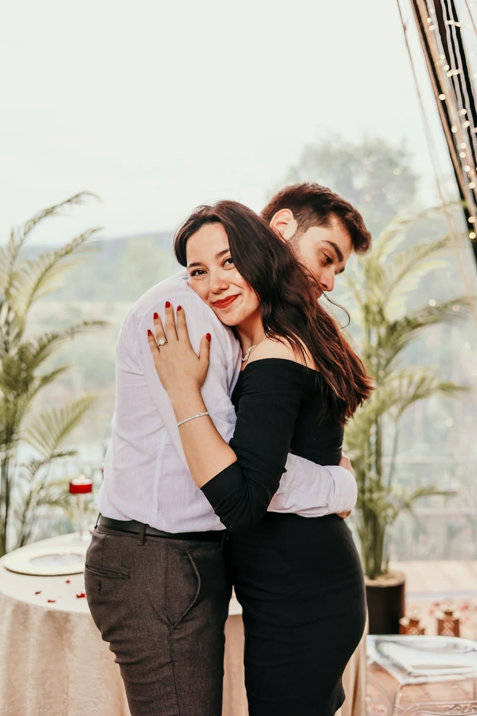 Nişan yüzüğü takan bir kadın partnerine sarılıyor.